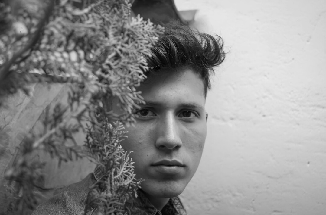 Portrait of a German man in his thirties with short dark hair and a knit sweater