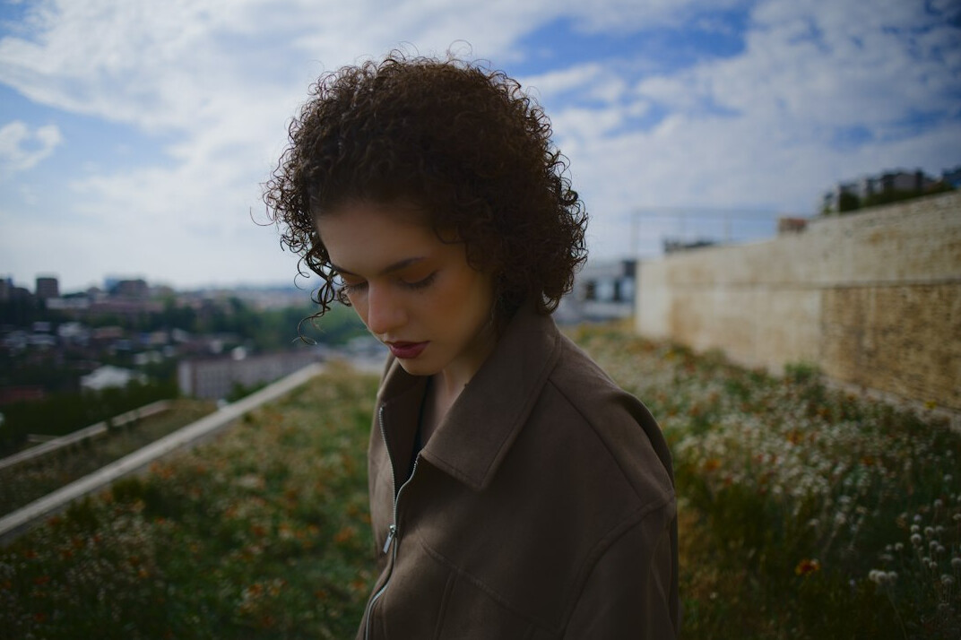 Portrait of a young woman with dark curly hair and a camel coat